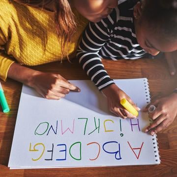 Two kids writing Alphabets
