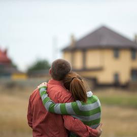 two partners standing in front of a house